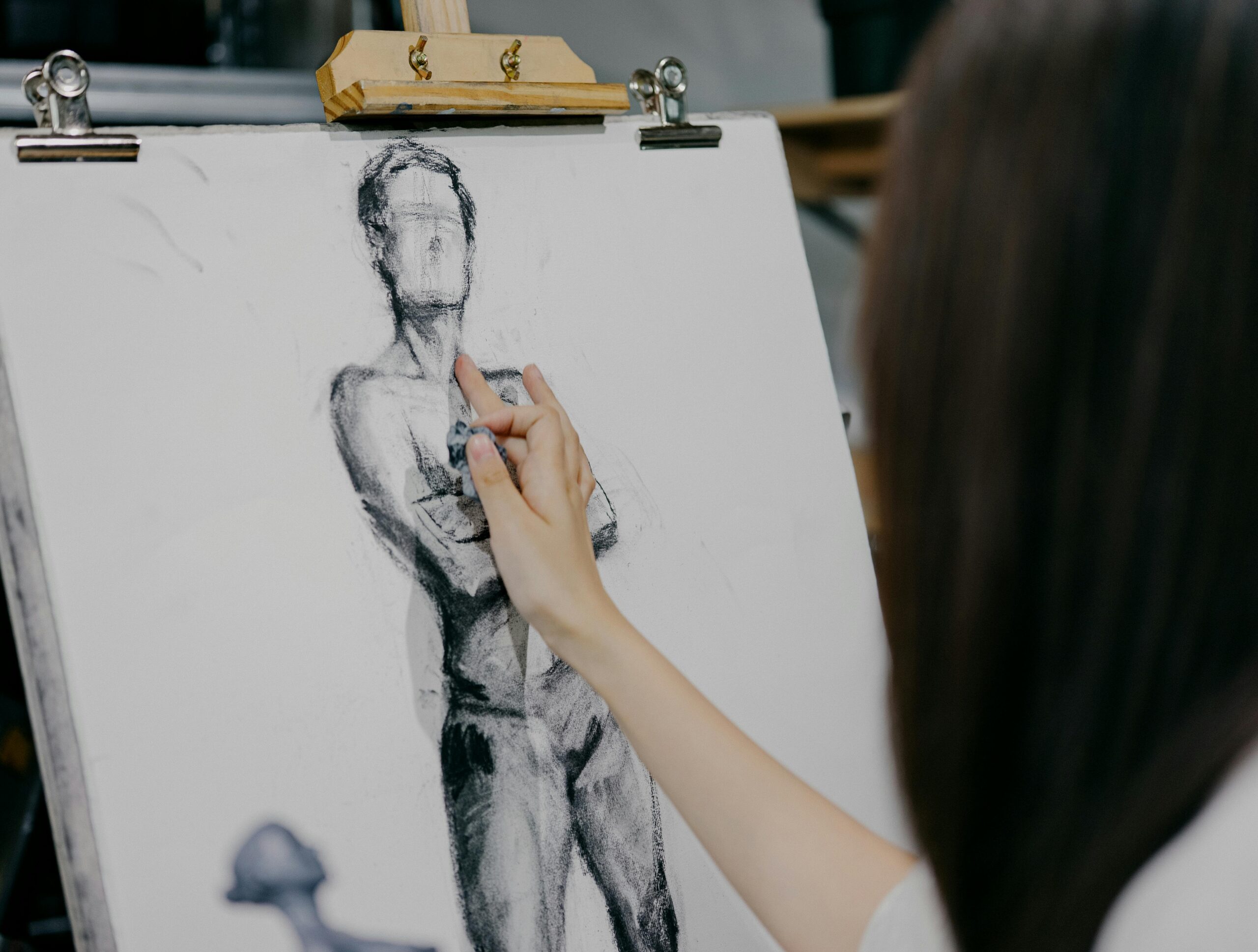 A focused artist sketching a human figure on canvas in a Shinjuku art studio in Tokyo, Japan.