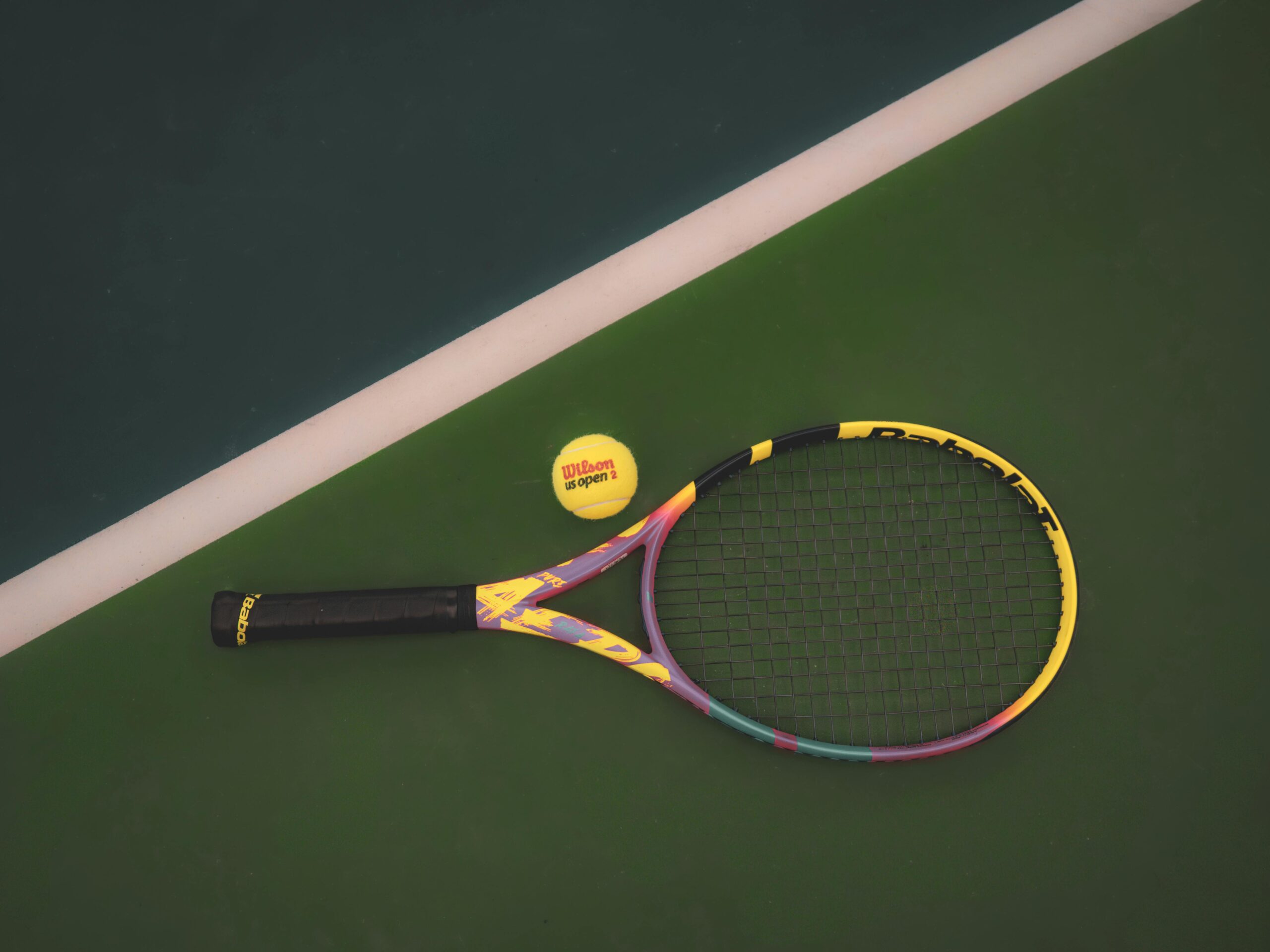 Tennis racket and ball on a vibrant green court, ready for a match.